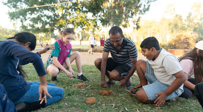 people sitting in a group on the grass at edenbrook park learning how to build a gfire