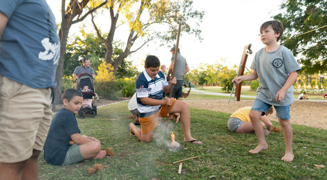 a community event in edenbrook estate in rockhampton where a little boy is kneeling beside a fire he has just learnt to build