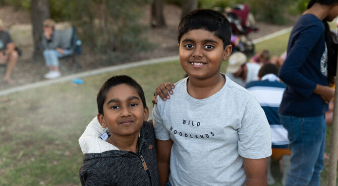 two young indian boys standing together smiling for a photo at edenbrook estates community event in rockhampton