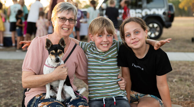 grandmother sitting with smiling grand children and pet dog at edenbrook estate community event in rockhampton