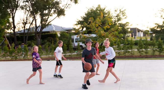 boy bouncing basketball with other kids on court located in edenbrook estate in rockhampton